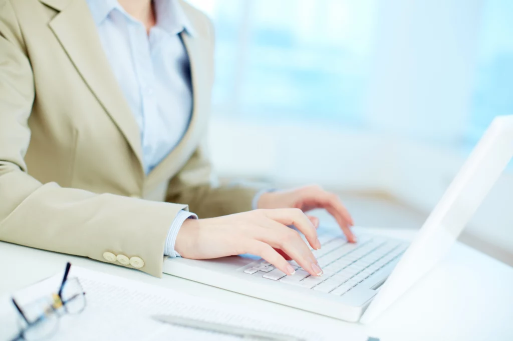 辦公室內一名上班族使用筆電鍵盤進行文字輸入的工作情境