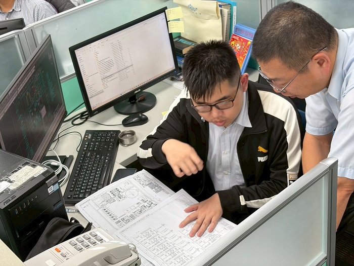 台灣化學纖維公司高級工程師張榮華指導明志科大留任公費生，帶領  檢視設計圖面以培養獨立作業力。（圖/明志科大提供）