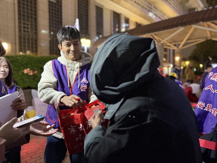 王家梁將人安基金會愛心年禮與應急紅包雙手遞向寒士。(圖/人安基金會提供)
